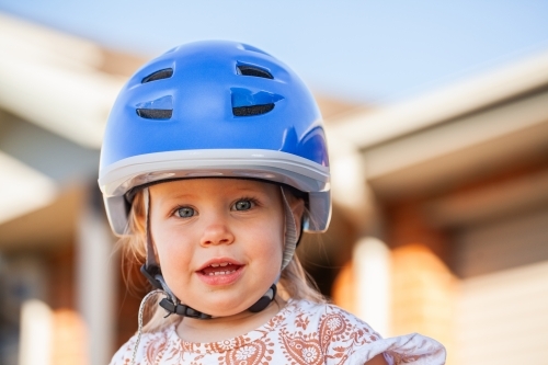 Toddler girl outside wearing bike helmet for safety while riding - Australian Stock Image