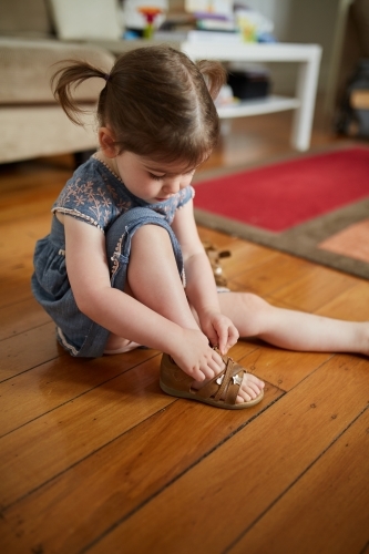Toddler putting sandals on - Australian Stock Image