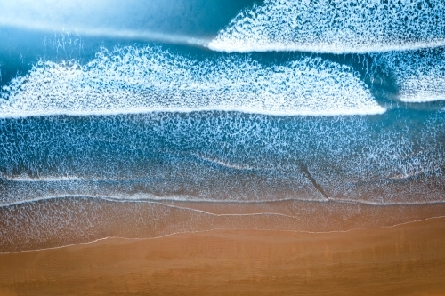 Top Down of sandy shore and waves washing up the beach - Australian Stock Image