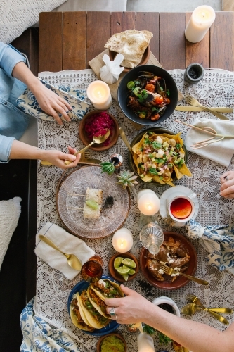 Top-down view of a table with various dishes and people eating. - Australian Stock Image