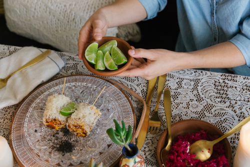 Top-down view of a table with various food and woman holding a small bowl of lime - Australian Stock Image