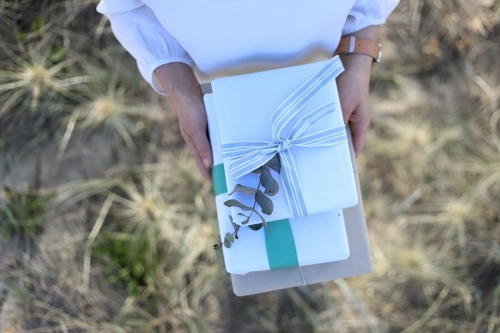 Top down woman holding presents with sea grass in background - Australian Stock Image