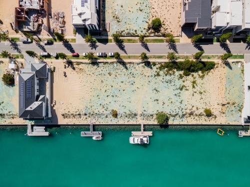 top shot of a beach with docked boats, trees, buildings and trees on a sunny day - Australian Stock Image