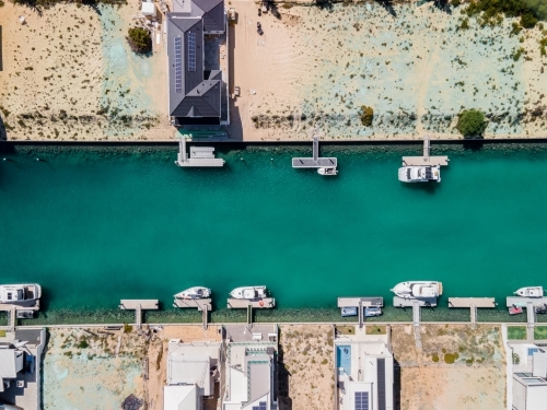 top shot of a beach with docked boats, trees, house and trees on a sunny day - Australian Stock Image