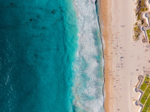 top shot of a beach with waves. people on white sand shoreline and green grass. on a sunny day - Australian Stock Image