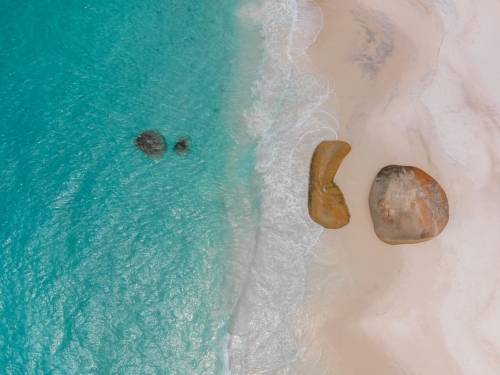 top shot of a beach with white sand shoreline, waves and rocks - Australian Stock Image