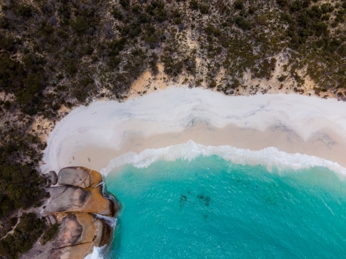 top shot of a beach with white sand shoreline, waves, bushes, trees and rocks - Australian Stock Image