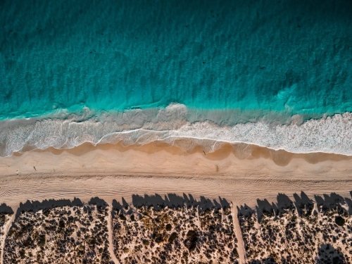 top shot of a shoreline waves with white sand, grass and ocean water - Australian Stock Image