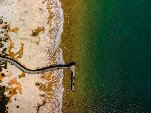 top view shot of a beach walkway with bushes, trees and waves on a sunny day - Australian Stock Image