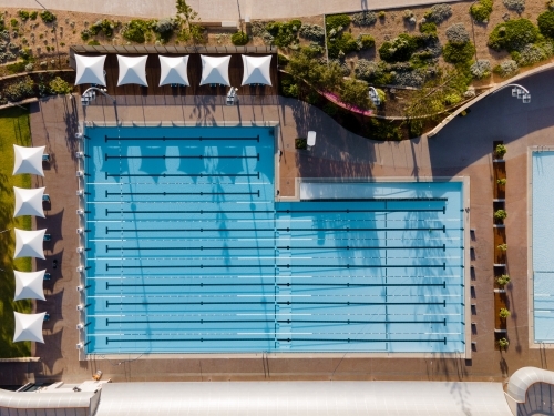 top view shot of a swimming pool with white shade in the sides and trees around it - Australian Stock Image