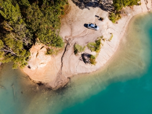 top view shot of blue water with green trees and white rock formation with a parked car - Australian Stock Image