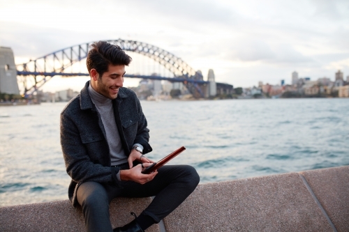 Tourist checking phone with the Sydney Harbour Bridge in background - Australian Stock Image