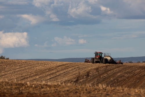 tractor ploughing soil in farm paddock - Australian Stock Image