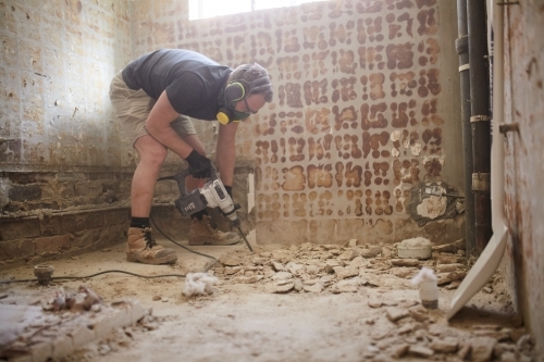 Tradesman jackhammering a floor in a construction site - Australian Stock Image