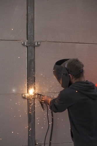 Tradesman welding fencing in a home environment - Australian Stock Image