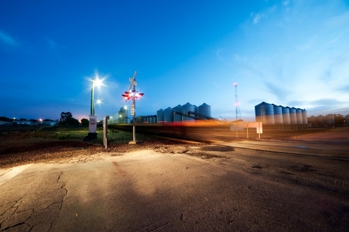 Train speeds by level crossing in the early morning light - Australian Stock Image