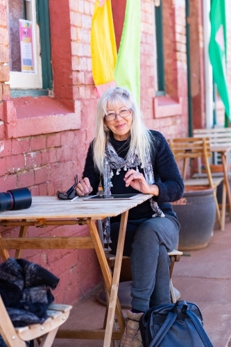 traveller sitting at table outside colourful building - Australian Stock Image