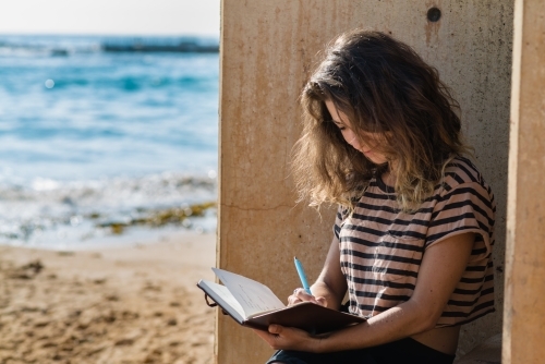traveller writing in diary by the ocean - Australian Stock Image