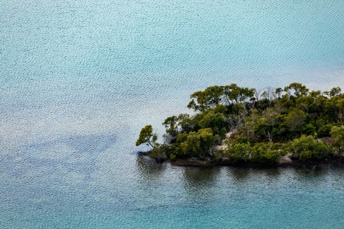 tree covered island in blue sea - Australian Stock Image