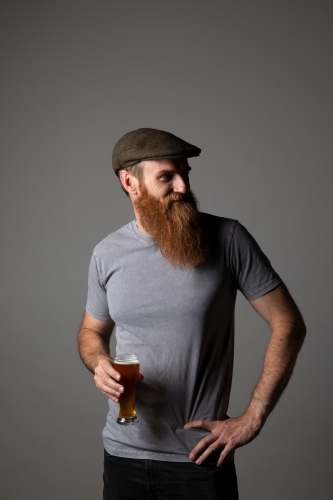 Trendy guy holding a glass of beer, relaxed and happy - Australian Stock Image