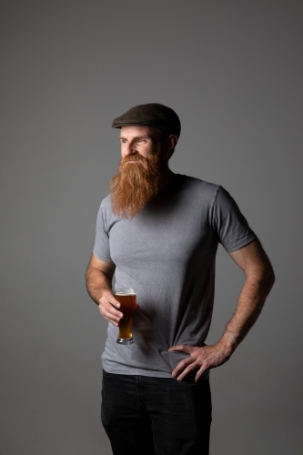 Trendy guy holding a glass of beer, relaxed and happy - Australian Stock Image