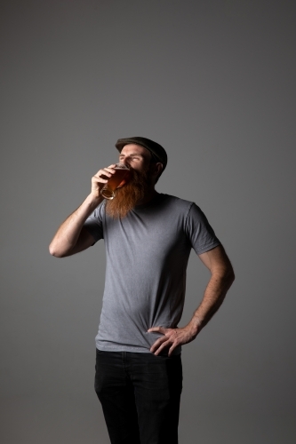Trendy guy holding a glass of beer, relaxed and happy - Australian Stock Image