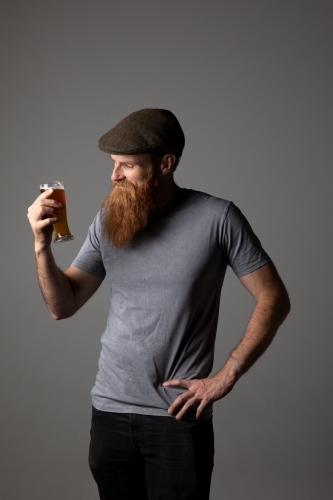 Trendy guy holding a glass of beer, relaxed and happy