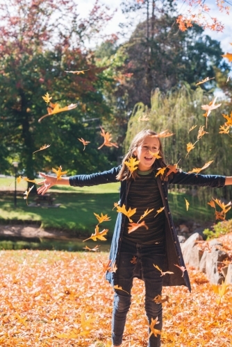 tween girl throwing autumn leaves