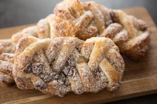 Twisted Pastries with Chocolate and Icing sugar on a board - Australian Stock Image