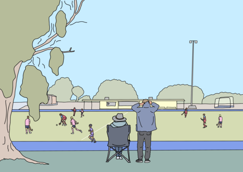 Two adults watching children play winter hockey game from sidelines - Australian Stock Image