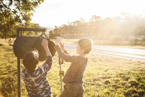 Two boys checking the mailbox for mail in the golden afternoon light - Australian Stock Image