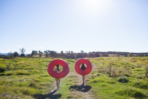 Two children walking on a track carrying inflatable rings - Australian Stock Image