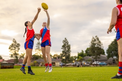 two female footy players stretching up to tap the ball away - Australian Stock Image