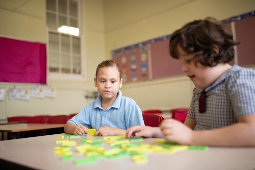 Two girl school students collaborating with coloured word tiles - Australian Stock Image