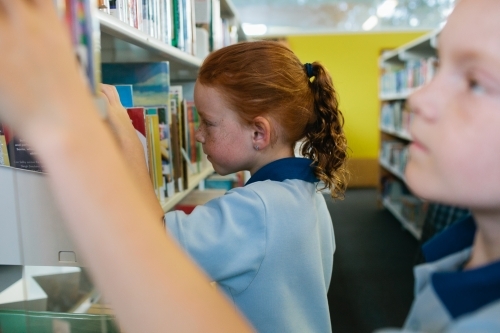 Two girls choosing books at the Library