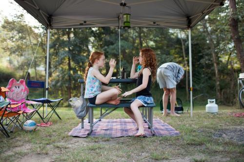 Two girls playing a clapping game at a campsite - Australian Stock Image