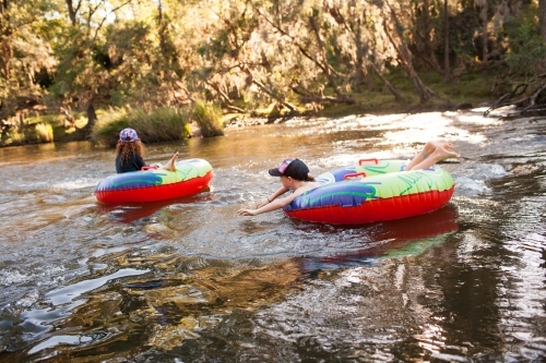 Two girls playing on inflatable rings on a river