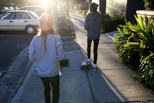 Two girls walking away on a footpath - Australian Stock Image