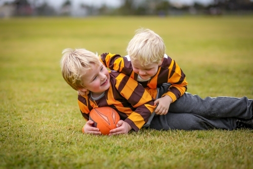 Two little boys playing Aussie Rules Football on field - Australian Stock Image