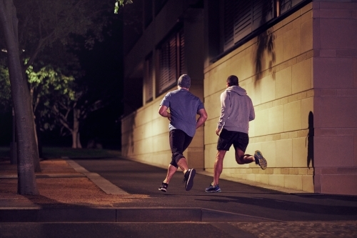 Two men fitness training in urban city at night - Australian Stock Image