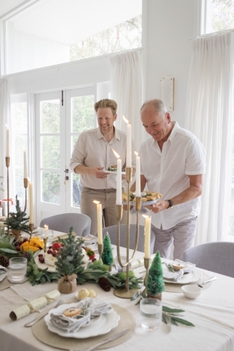 Two men setting up Christmas table together - Australian Stock Image