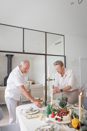 Two men setting up Christmas table together - Australian Stock Image