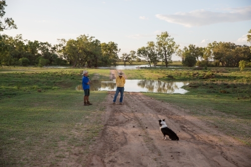 Two men talking at a flooded creek in the country - Australian Stock Image