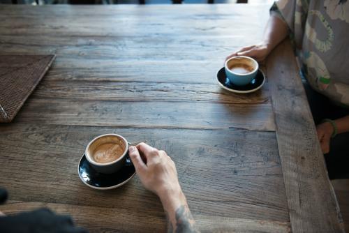 Two people drinking coffee at a wooden table