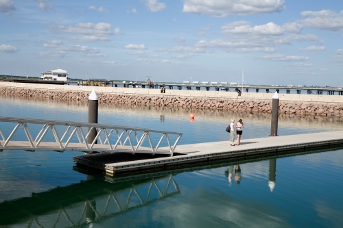 Two people standing at a distance on a pontoon with reflection - Australian Stock Image