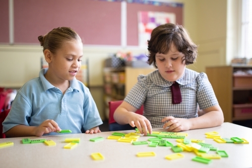 Two primary school girl students collaborating with coloured word tiles - Australian Stock Image