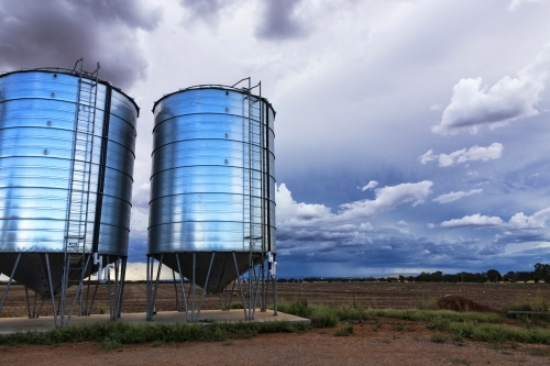 Two silos and farm land with storm clouds - Australian Stock Image