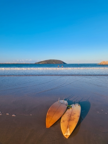 Two surfboards on the sand as the sun sets near the beach - Australian Stock Image