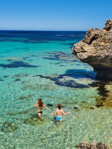 Two teenage girls wading in the ocean - Australian Stock Image