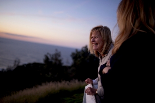 Two women at a lookout at dusk laughing - Australian Stock Image